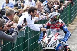John McGuinness wins his 18th TT title and is congratulated by F1 driver Mark Webber(L)