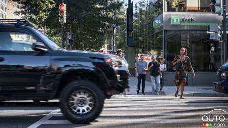 An SUV passes infront of pedestrians