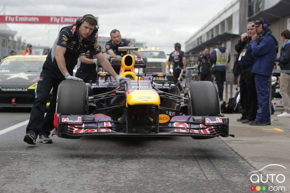 Sebastian Vettel's car behing pushed by mechanics after technical inspection.