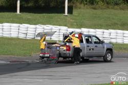 Des travailleurs de piste ramnassent des débris de la voiture de Hugo Vannini, VTI Motorsports Ford durant la course