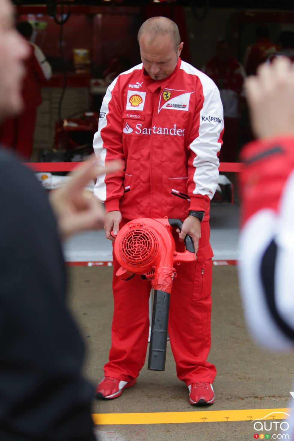 A mechanic from the Ferrari team dries the pavement in front of their pit box.