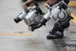 Red Bull Racing mechanics use blowers to dry the pavement on pit lane.
