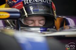 Sebastian Vettel sits in his car in the Infiniti Red Bull garage.