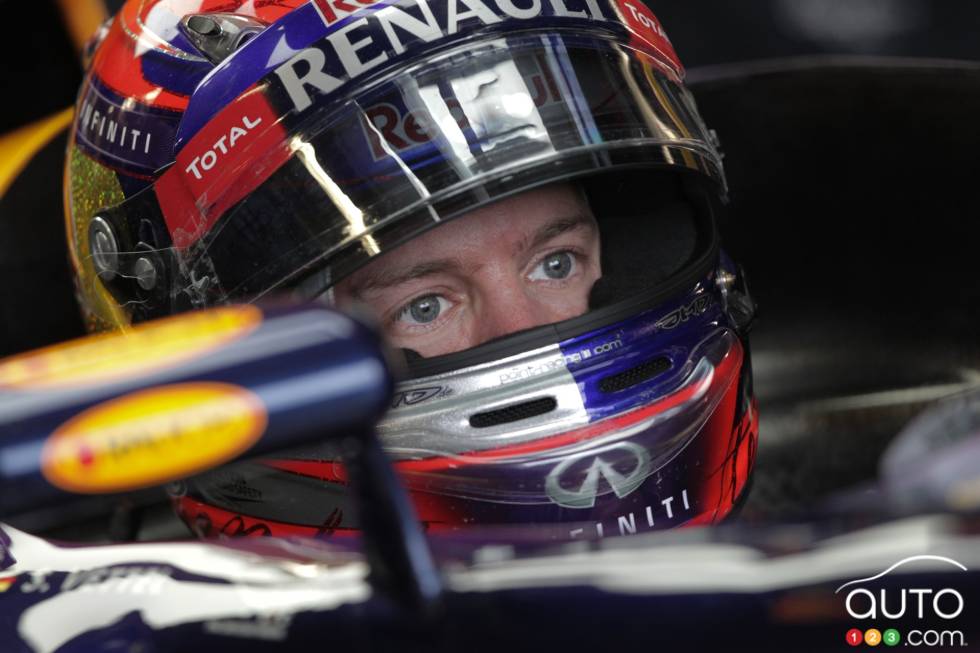 Sebastian Vettel sits in his car in the Infiniti Red Bull garage.