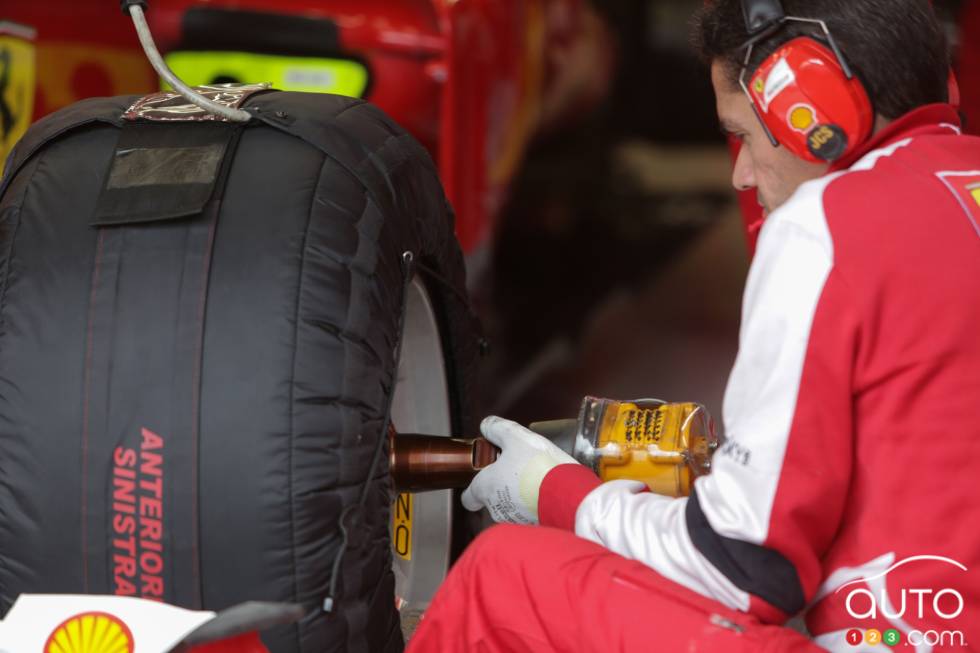 un mécano Ferrari pose une roue.