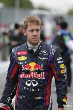 Sebastian Vettel walks back to his garage after his car was held at the technical inspection down pit lane.